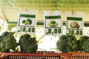 Vegetais frescos com etiquetas de preço em feira, representando o impacto da inflação no custo de vida