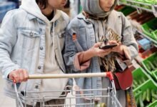 Casal escolhendo produtos no supermercado com carrinho de compras cheio, representando planejamento de orçamento familiar