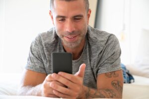 Tinder depois dos 40: homem usando o celular em casa