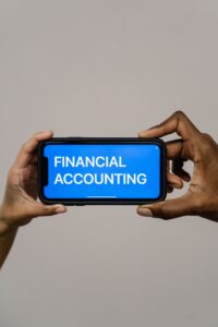 Duas pessoas segurando smartphone com interface de contabilidade financeira, representando a unificação de contas bancárias