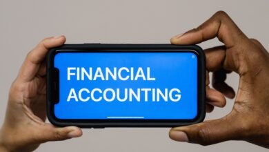 Duas pessoas segurando smartphone com interface de contabilidade financeira, representando a unificação de contas bancárias