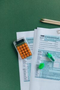 Formulários de imposto de renda com calculadora sobre a mesa, representando o cálculo da isenção do IR 2026