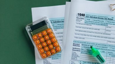 Formulários de imposto de renda com calculadora sobre a mesa, representando o cálculo da isenção do IR 2026
