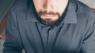 Homem confuso segurando cartão de crédito e olhando para o celular, representando dúvida sobre dívida no rotativo