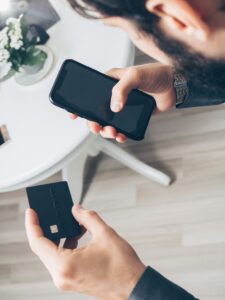 Homem segurando smartphone e cartão, representando o uso de aplicativos bancários e finanças digitais