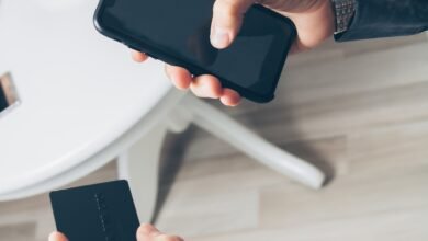 Homem segurando smartphone e cartão, representando o uso de aplicativos bancários e finanças digitais