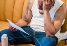 Pessoa sentada à mesa analisando contas e boletos com expressão preocupada